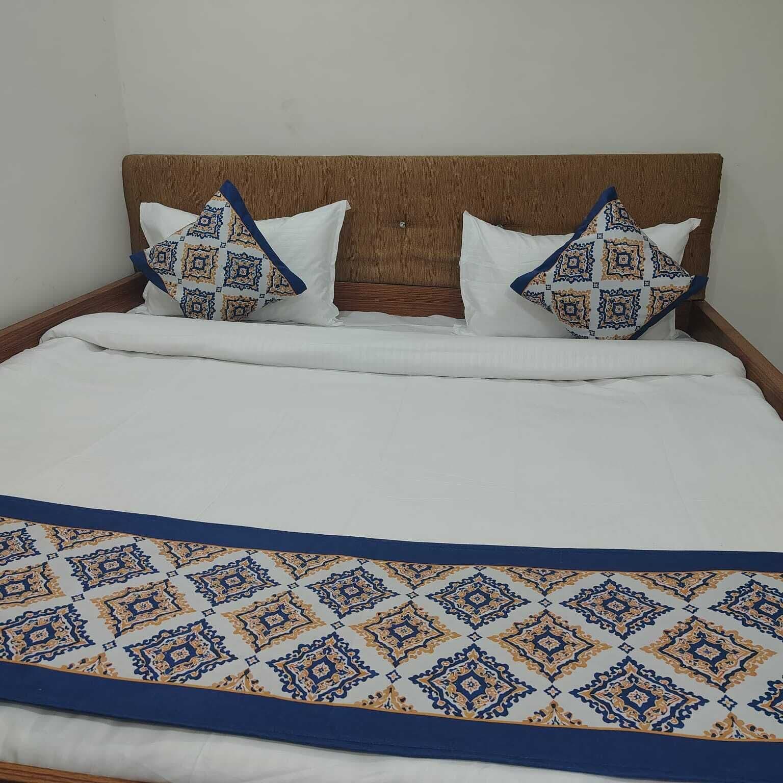 A bed with a patterned bedspread and two pillows with a geometric design.