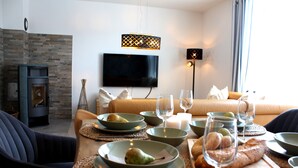 A dining area with a table set for two, a television mounted on the wall, and a fireplace. - Semi-detached house for groups with 4 bedrooms (Jesendorf)