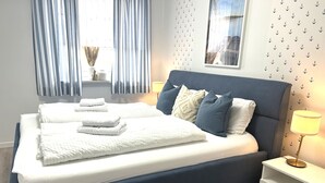 A modern bedroom with a large bed, bedside tables, and curtains. - Semi-detached house for groups with 4 bedrooms (Jesendorf)