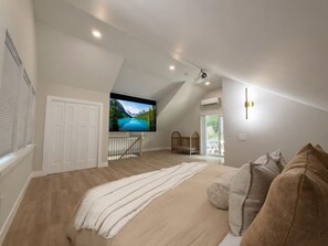 Ein Schlafzimmer mit einem großen Bett, einem Fernseher, einem Babybett und Blick auf eine Berglandschaft.