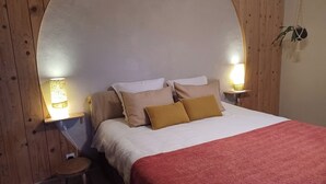 A bedroom with a curved headboard, two bedside lamps, a small stool, and a red blanket. - Eco-Honeymoon - 10 min. from the Bamboo Garden - for 4, 6, or 8 people (Anduze)