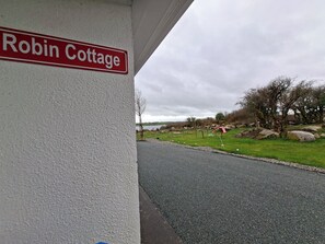 Ein Schild mit der Aufschrift 'Robin Cottage' an einer Gebäudefassade.