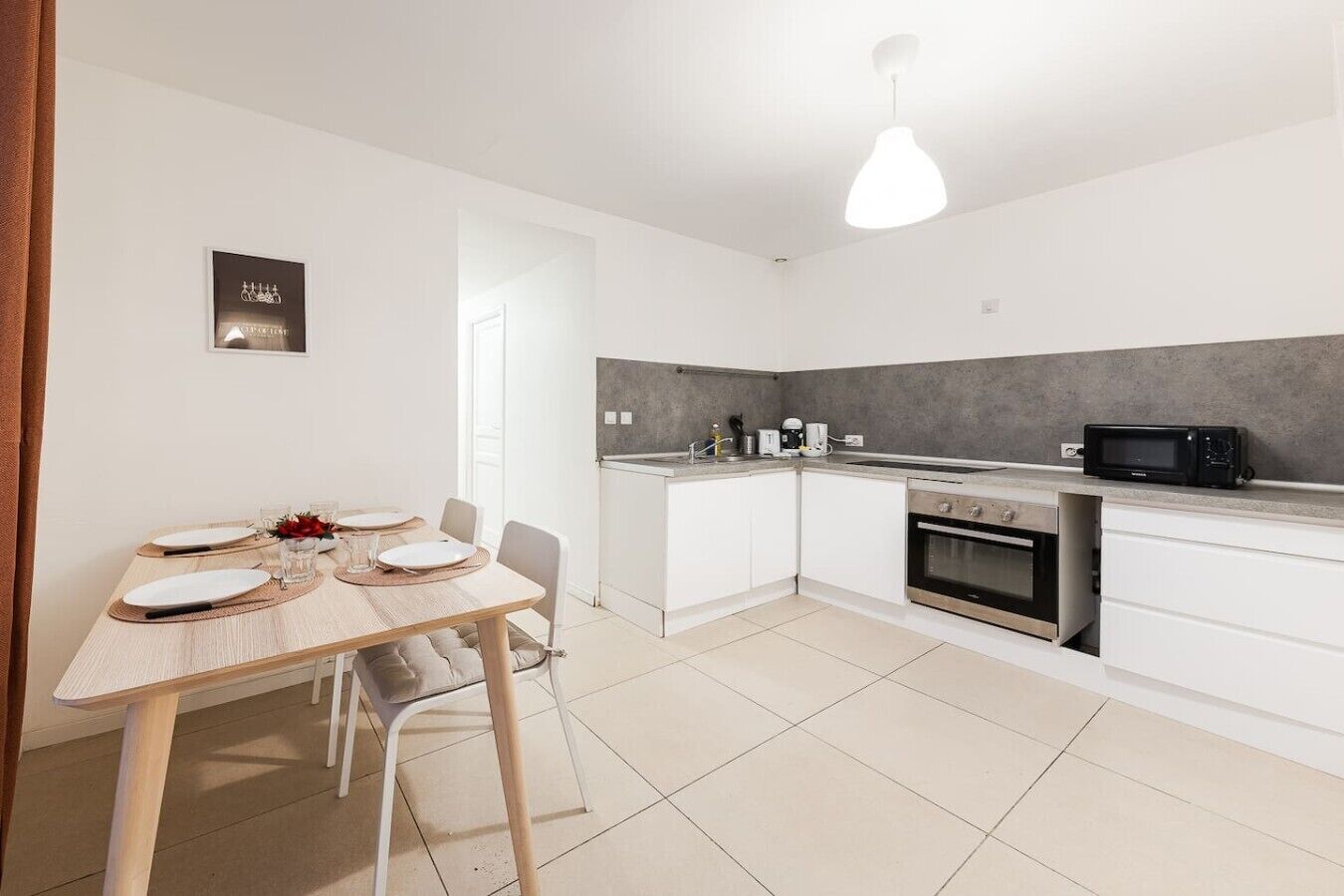 Una cucina moderna con pensili bianchi, un tavolo da pranzo per due persone e un forno a microonde sul piano di lavoro.