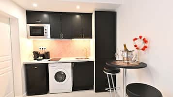A compact kitchen with a washing machine, microwave, and dark cabinets.