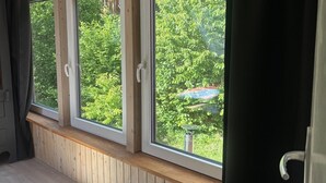 Et værelse med tre store vinduer, træpaneler og udsigt til grønne områder.