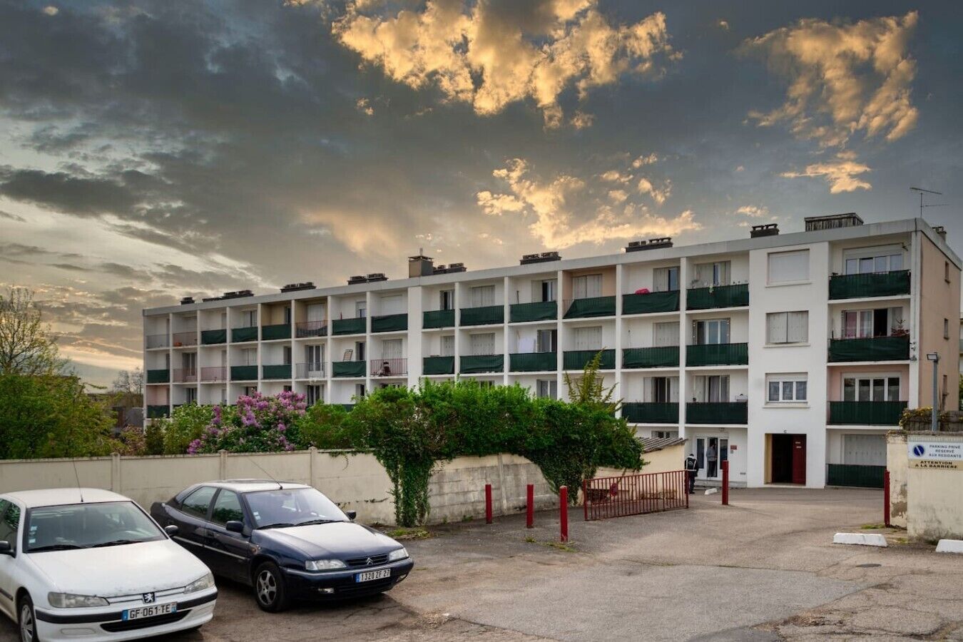 Un edificio residencial de varios pisos con balcones, un estacionamiento y un cartel que indica disponibilidad de espacios.