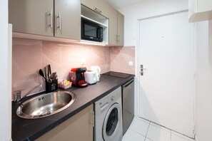 Une cuisine compacte équipée d’un évier, d’un four à micro-ondes, d’un grille-pain et d’un lave-linge.