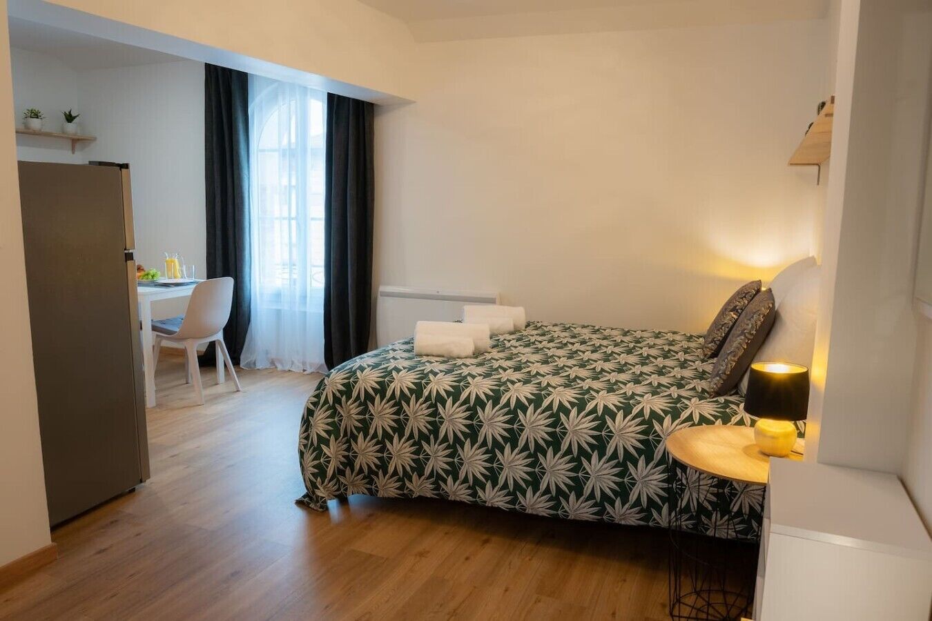 A bedroom with a bed, a desk, a chair, and a lamp.