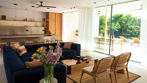 Een moderne woonkamer met een bank, stoelen, een salontafel en uitzicht op het groen.