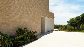 Een modern gebouw met een bakstenen gevel, een garagepoort en een aangelegde tuin met diverse planten.