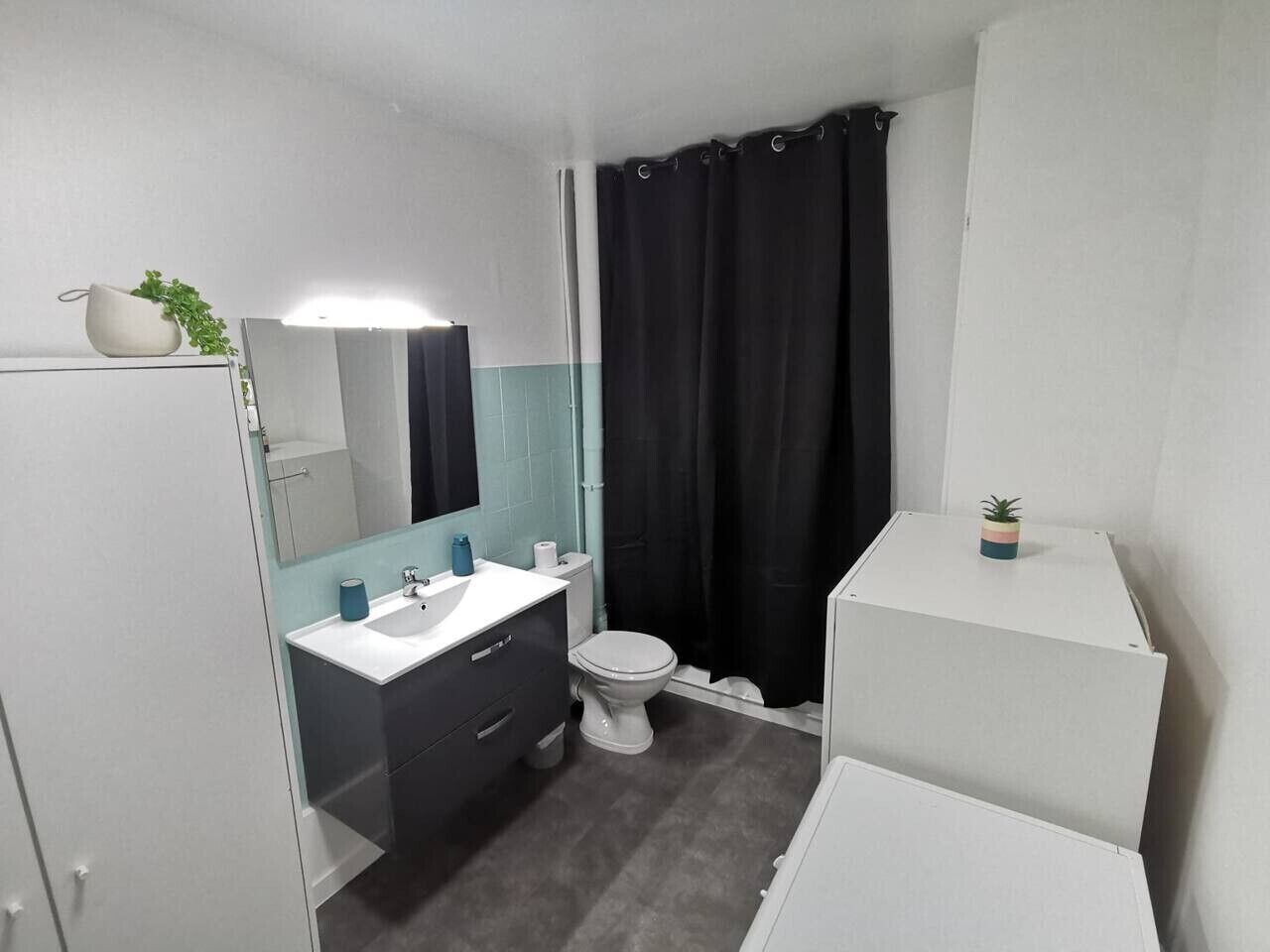 Een badkamer met toilet, wastafel en spiegel.