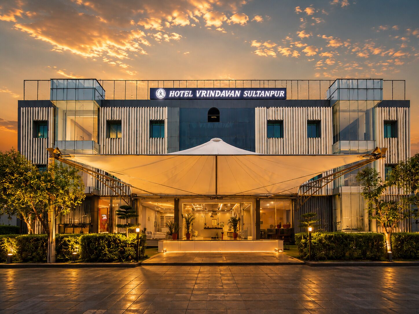 Un hotel moderno con un letrero llamativo, un acceso cubierto y un área exterior bien iluminada.