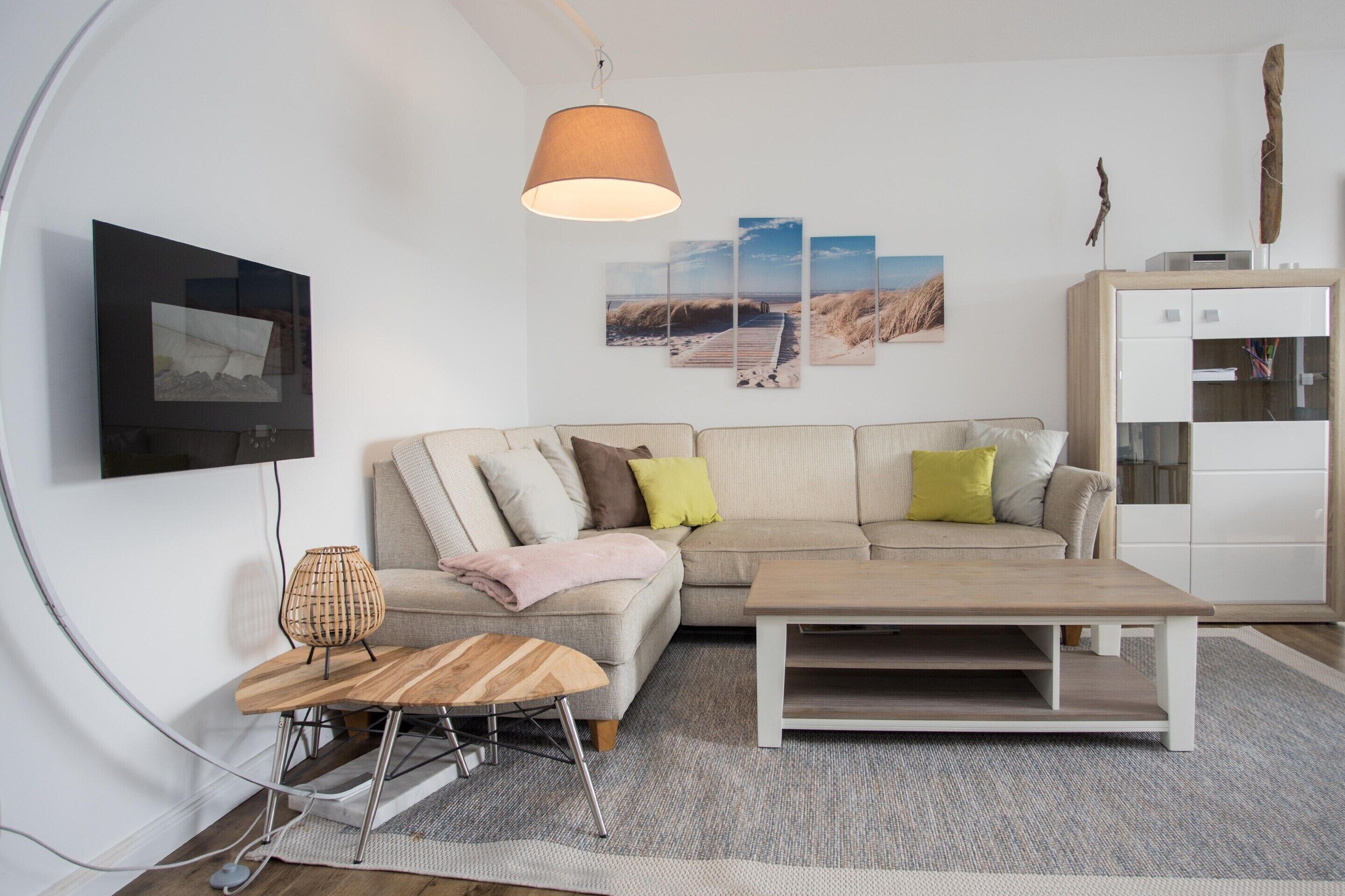 A modern living room with a sofa, a coffee table, a TV, and artwork on the wall.