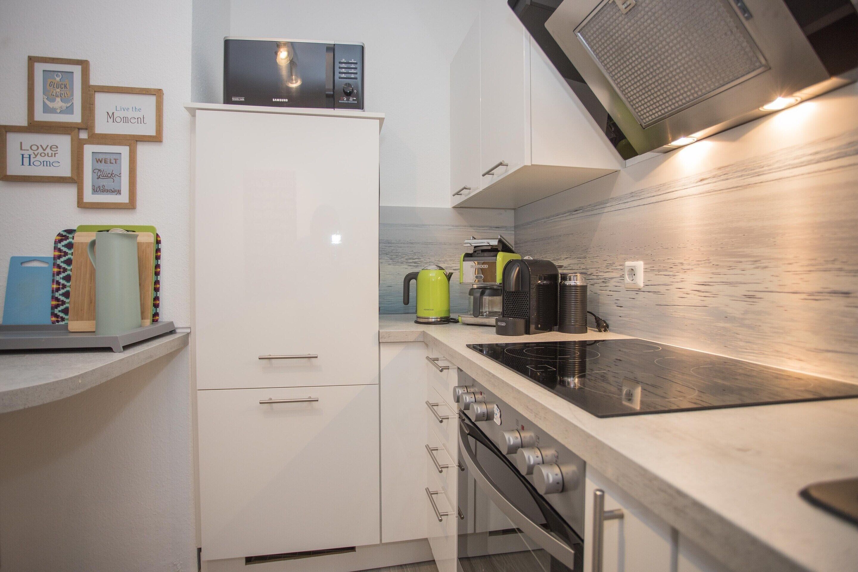 Una cucina moderna con forno a microonde, bollitore e macchina del caffè sul piano di lavoro.
