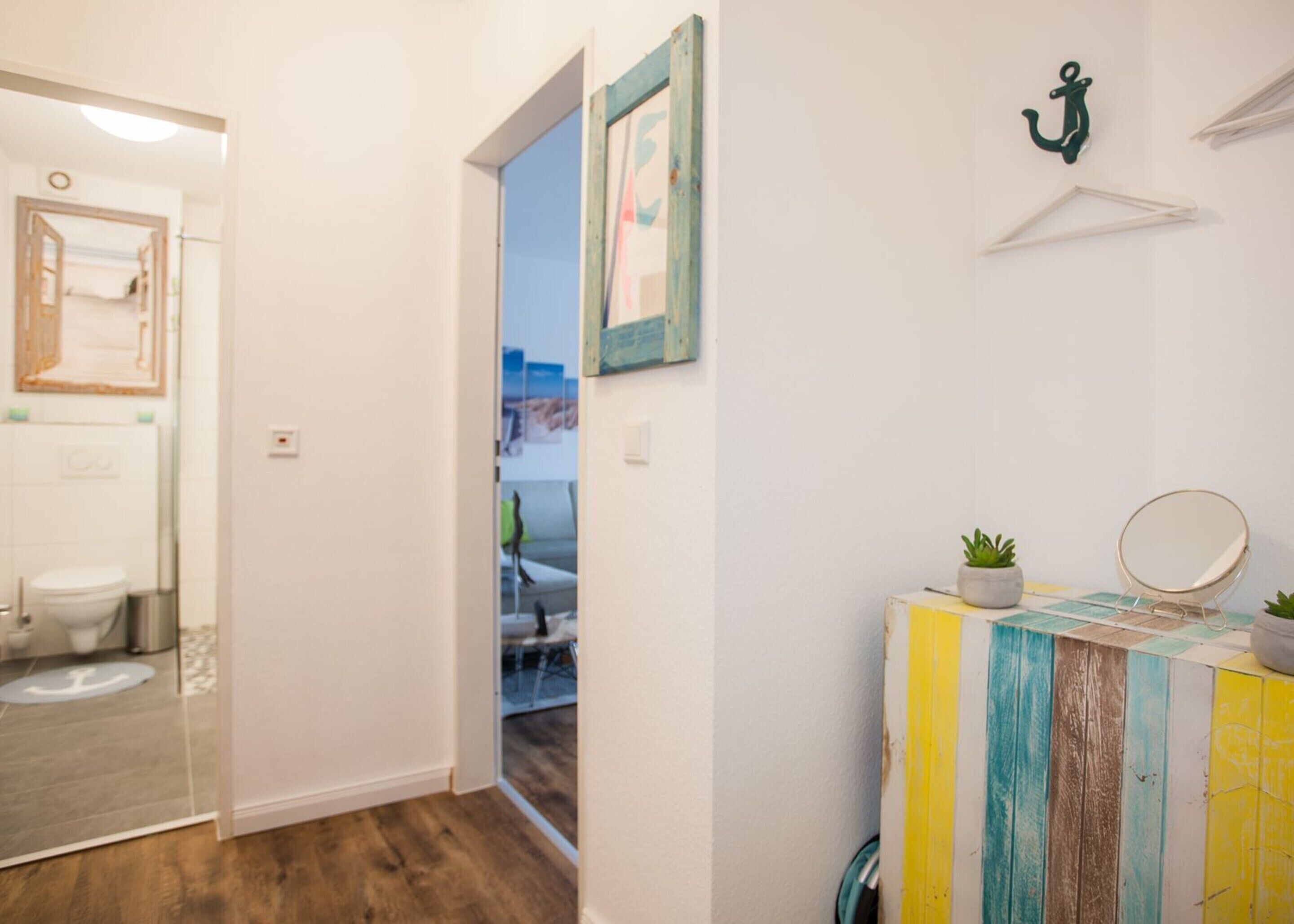 A bathroom with a toilet, a sink with a mirror, and a door leading to another room.
