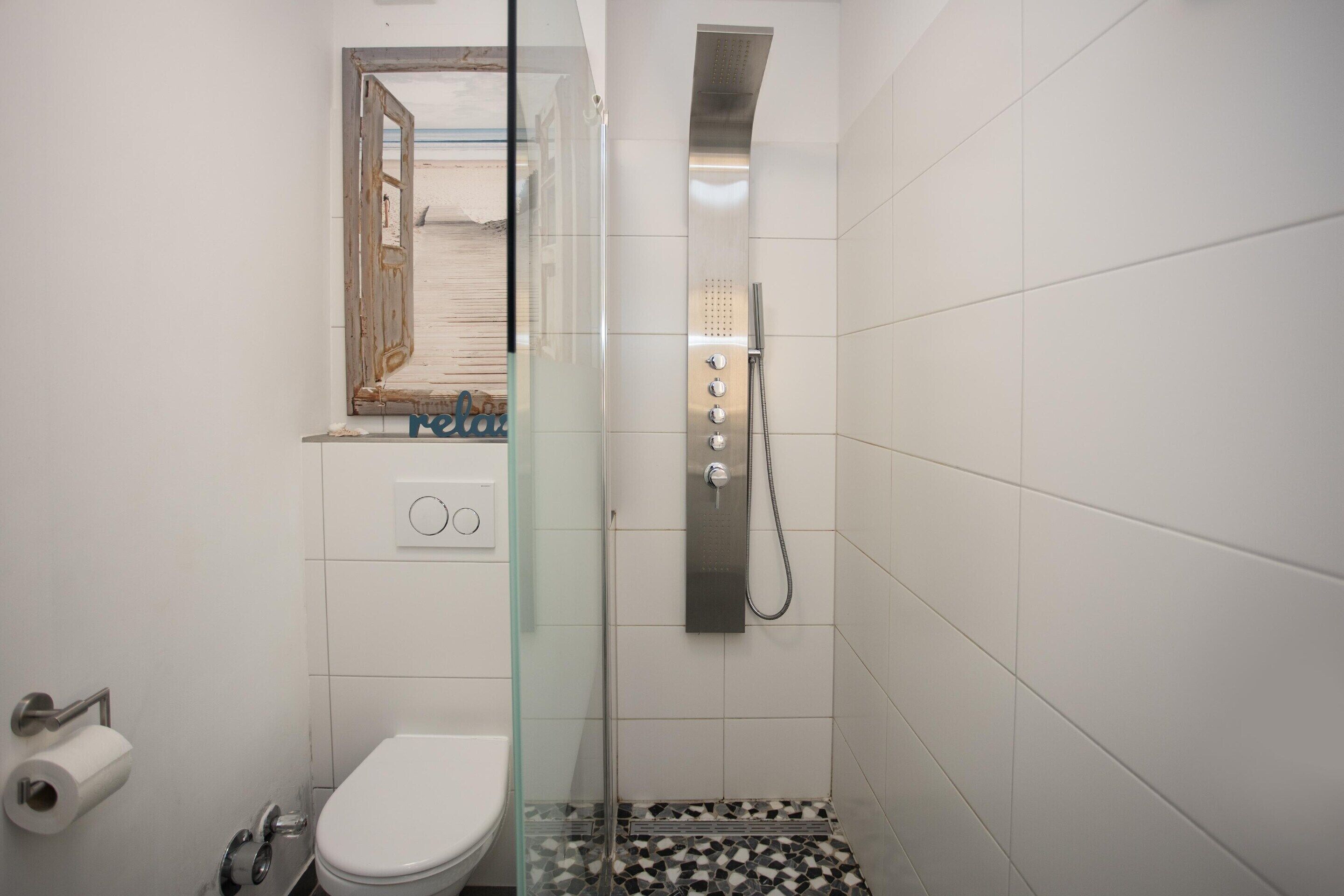 Ein Badezimmer mit Duschkabine, Toilette und fest installierter Bedienkonsole.