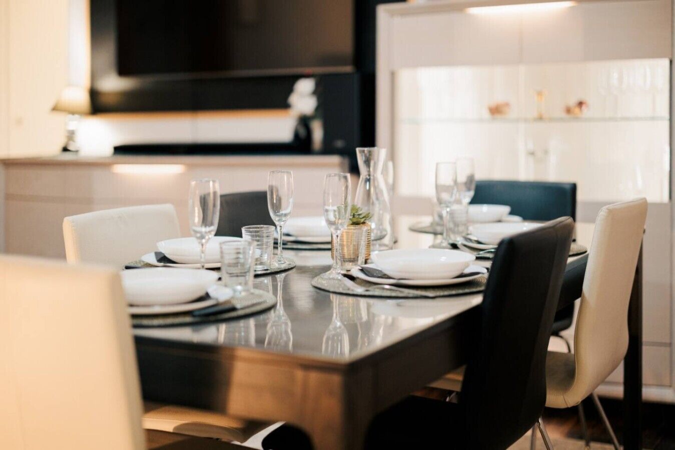 Une table à manger dressée avec des assiettes, des verres et un vase.