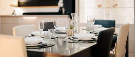A dining table set with plates, glasses, and a vase.
