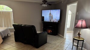 Ein Wohnzimmer mit Kamin, Fernseher, Ledersessel und Lampe.