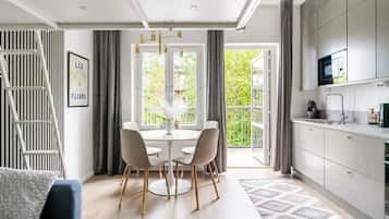 A modern kitchen with a dining area, a staircase, and a view of greenery.