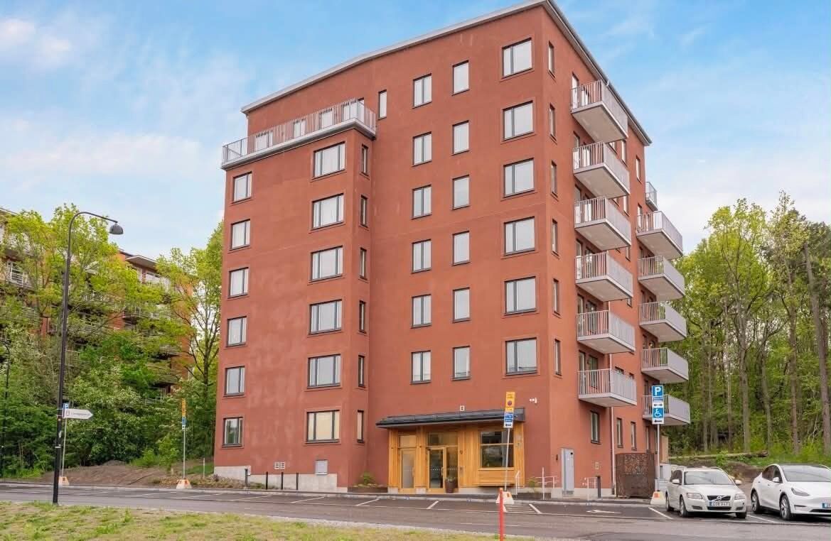 En byggnad med flera våningar, en röd fasad, balkonger och en entré i markplan.