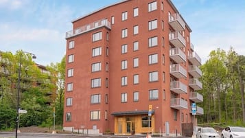 En byggnad med flera våningar, en röd fasad, balkonger och en entré i markplan.