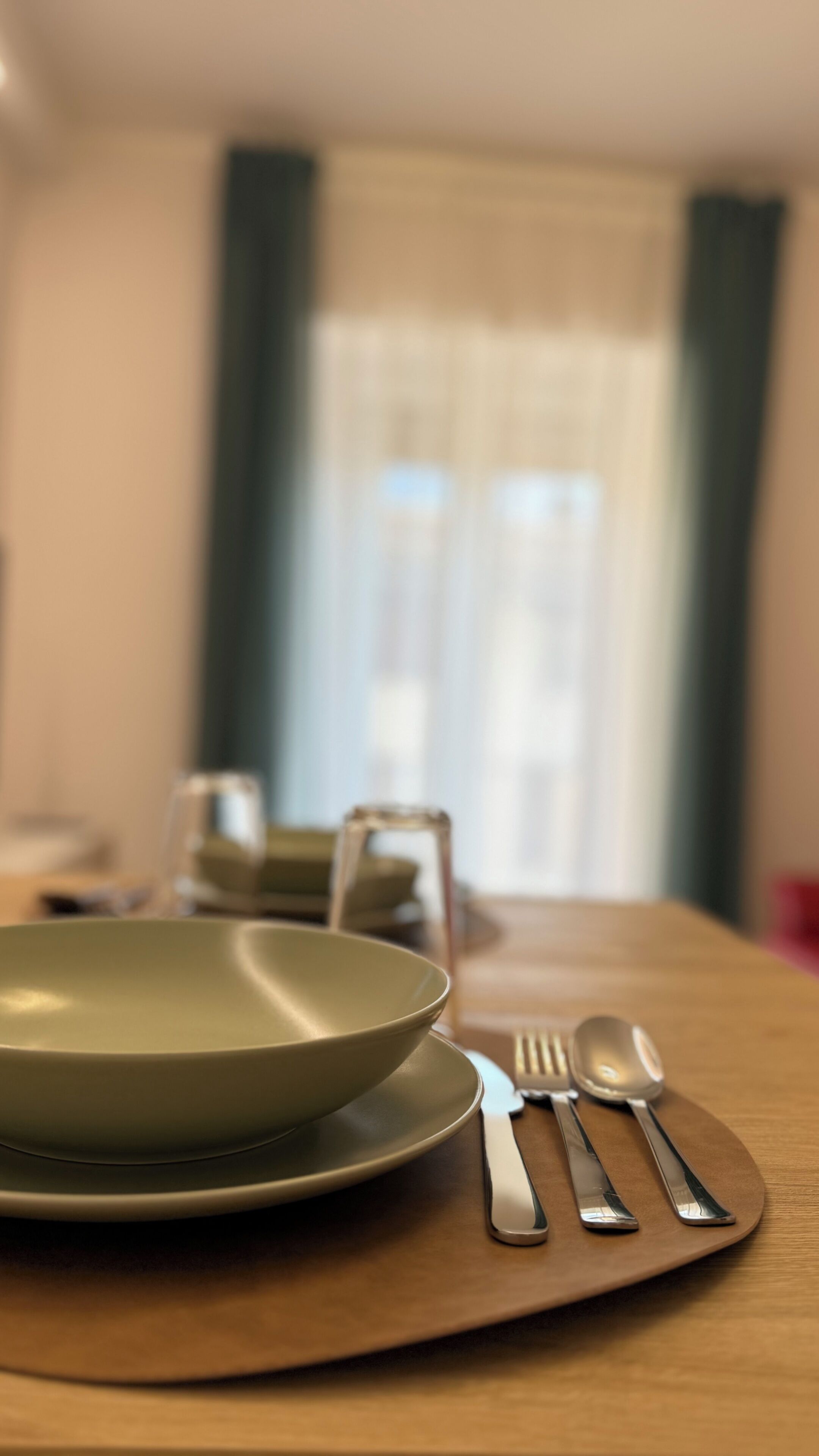 Una mesa de comedor con un plato, un tenedor y una cuchara sobre un mantel individual.