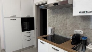 Eine moderne Küche mit weißen Schränken, einem eingebauten Backofen, einer Kaffeemaschine und einer Steckdose.
