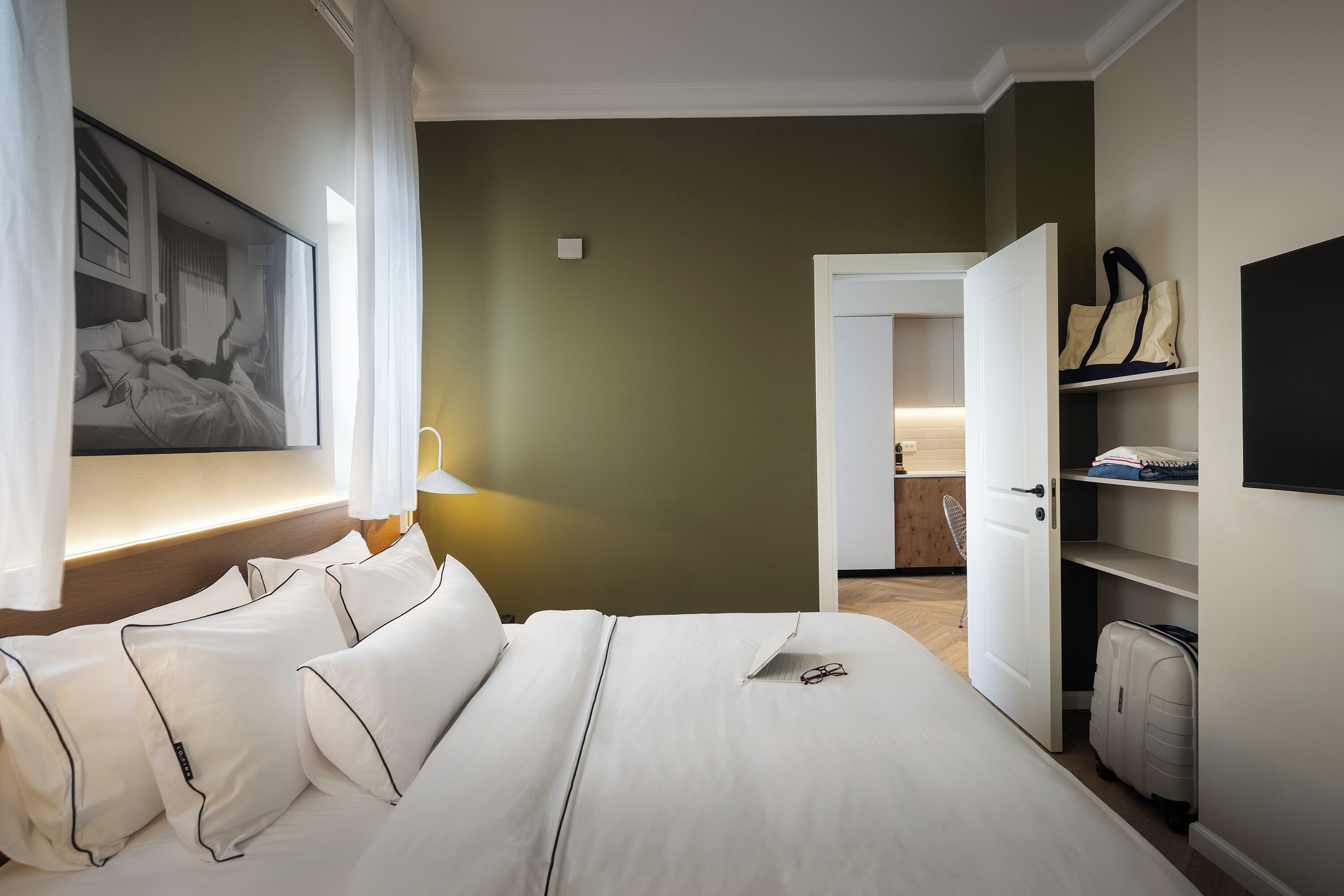 Een hotelkamer met een bed, een schilderij, een bureau en een kledingkast.