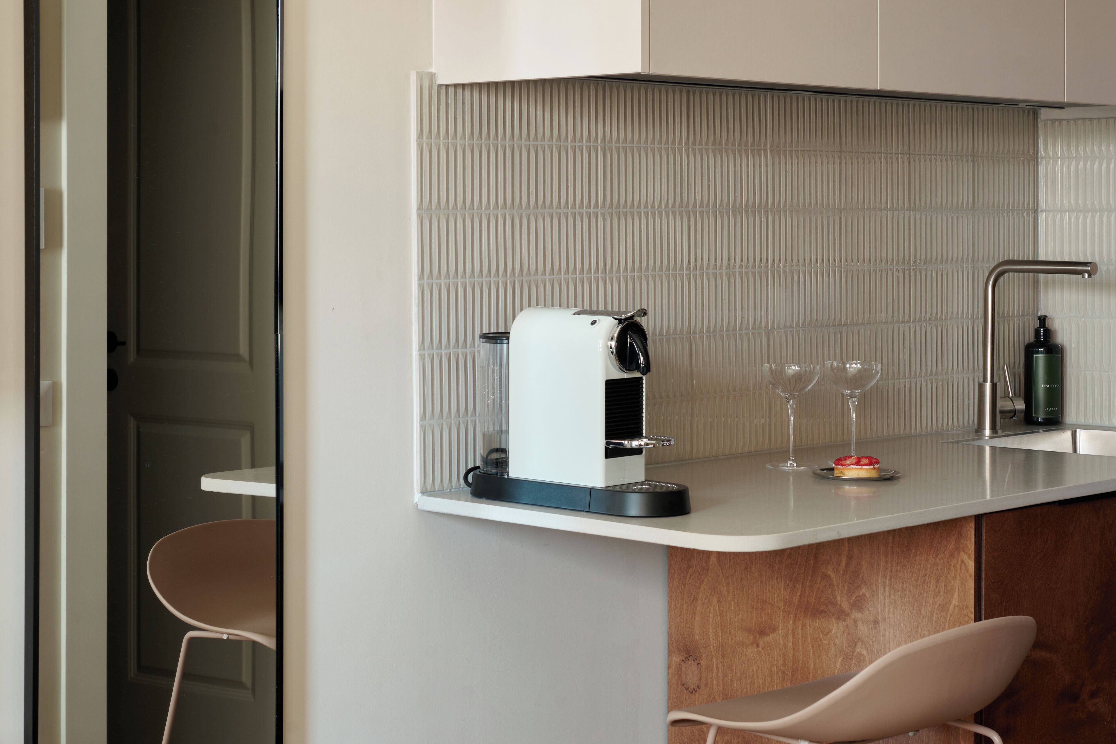 Eine moderne Küche mit integrierter Kaffeemaschine, Spüle und einer Bar.