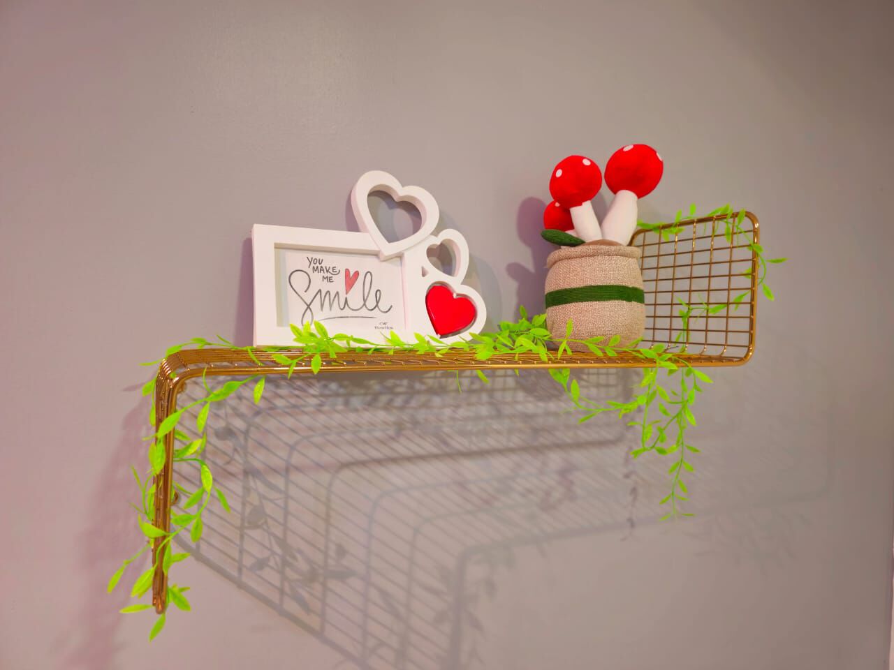 A shelf with a framed sign, a mug, and a basket with red mushrooms.