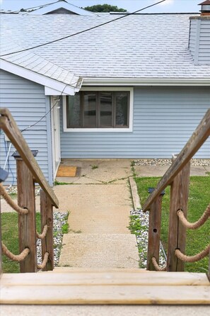 A residential house with a front porch, a window, and a pathway leading to the door.