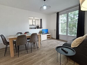 Ein modernes Wohnzimmer mit Essbereich, Fernseher und großem Fenster.