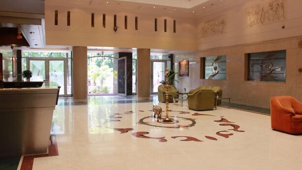 A spacious lobby with a reception desk, seating area, and large windows allowing natural light.
