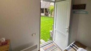 A room with a bed, a radiator, a door leading outside, and a small table with a tissue box. - Eco Garden Dilijan (Dilijan)