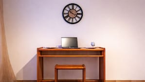 Un escritorio de madera con una computadora portátil, un globo terráqueo pequeño y un reloj en la pared.
