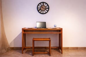 Un escritorio de madera con una computadora portátil, un globo terráqueo pequeño y un reloj en la pared.