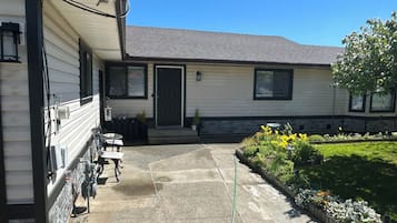 A residential building with a covered patio, outdoor seating, and a garden with flowers.