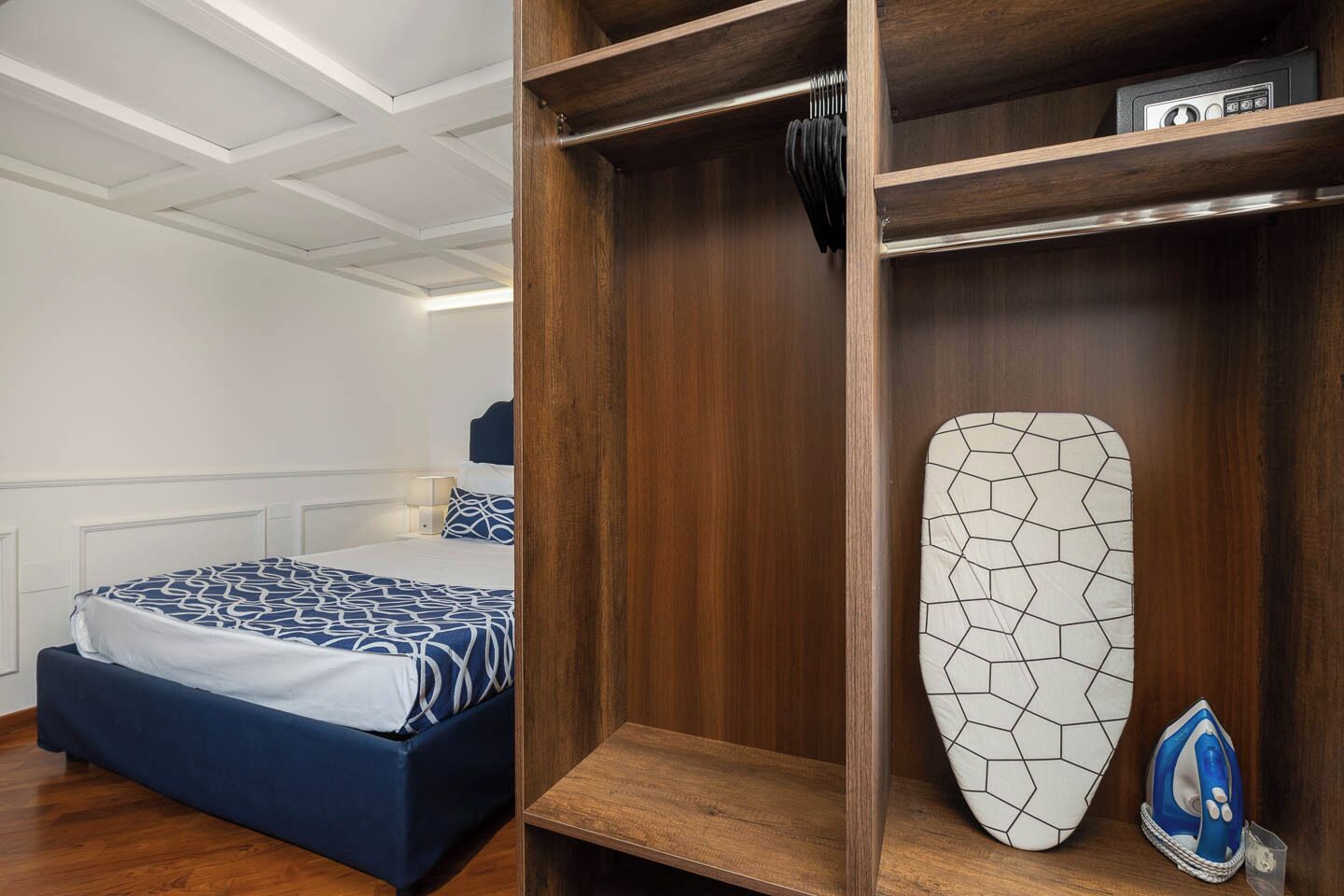 A bedroom with a bed, a wooden wardrobe, and a surfboard.