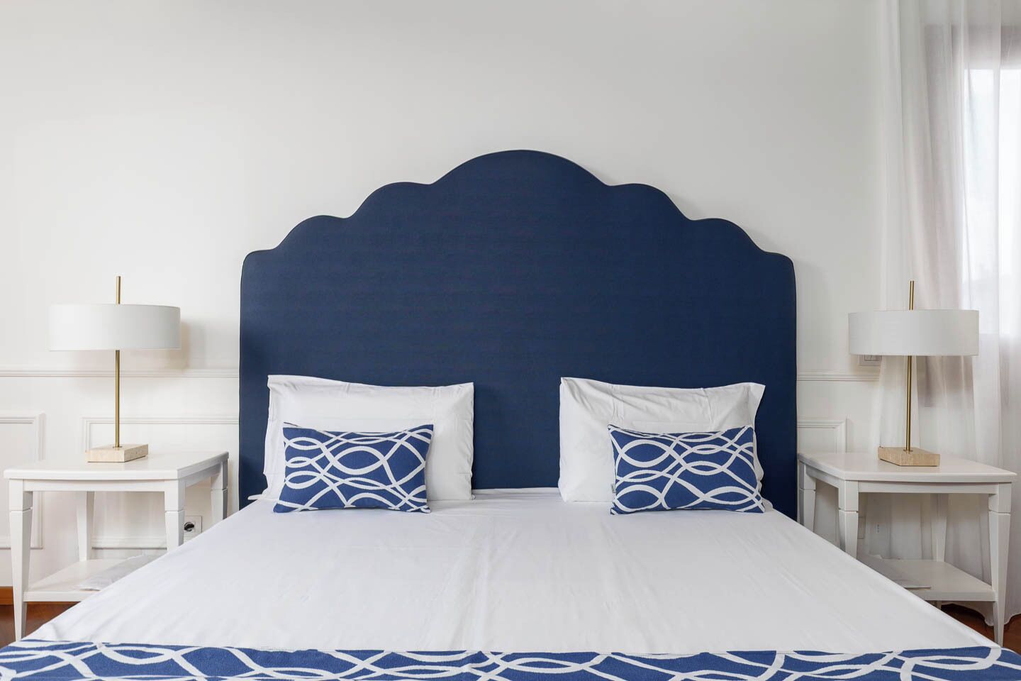 A bed with a blue headboard, white bedding, and two matching pillows.