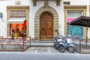 Uma fachada com uma placa indicando 'STUDIO GELATO' e uma scooter estacionada na frente.