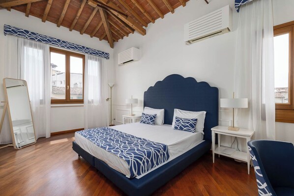 A bedroom with a large bed, bedside tables, a mirror, and a window with curtains.