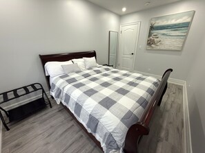 Ein Schlafzimmer mit einem Bett, einer Bank, einer Tür und einem Bild an der Wand.