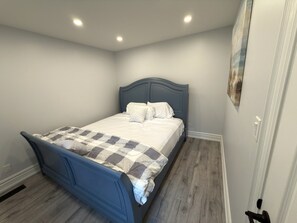 Ein Schlafzimmer mit einem Bett, einem Kopfteil und einem Bild an der Wand.