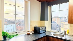 Eine Küche mit zwei großen Fenstern, einem Toaster, einer Spüle und einem Geschirrspüler.