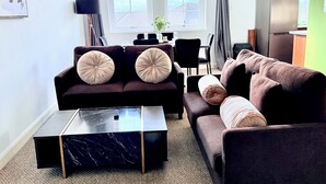 Ein Wohnzimmer mit einer Couch, einem Couchtisch und einem Essbereich mit Tisch und Stühlen.