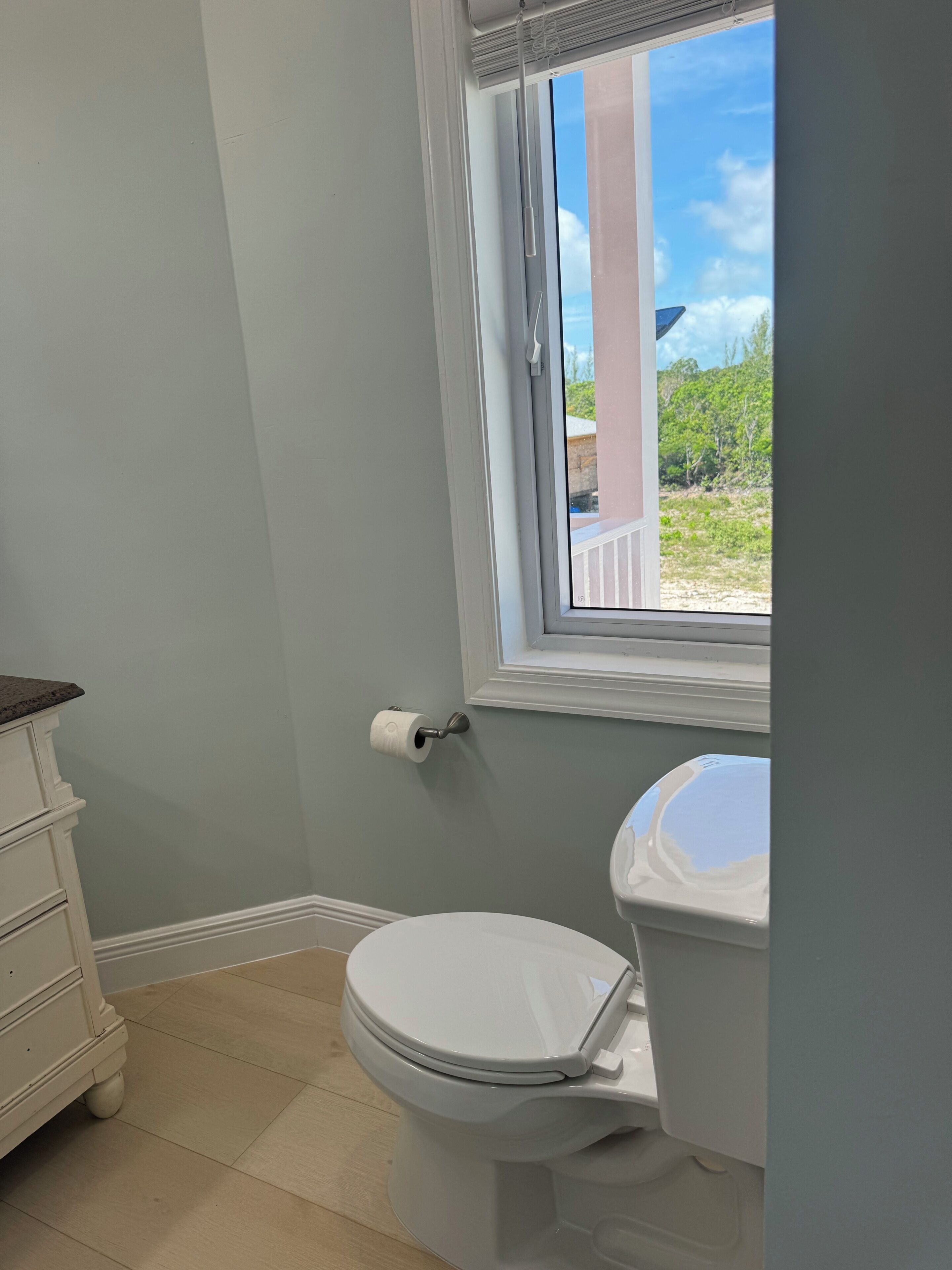Une salle de bain avec des toilettes, une fenêtre et un meuble de rangement.
