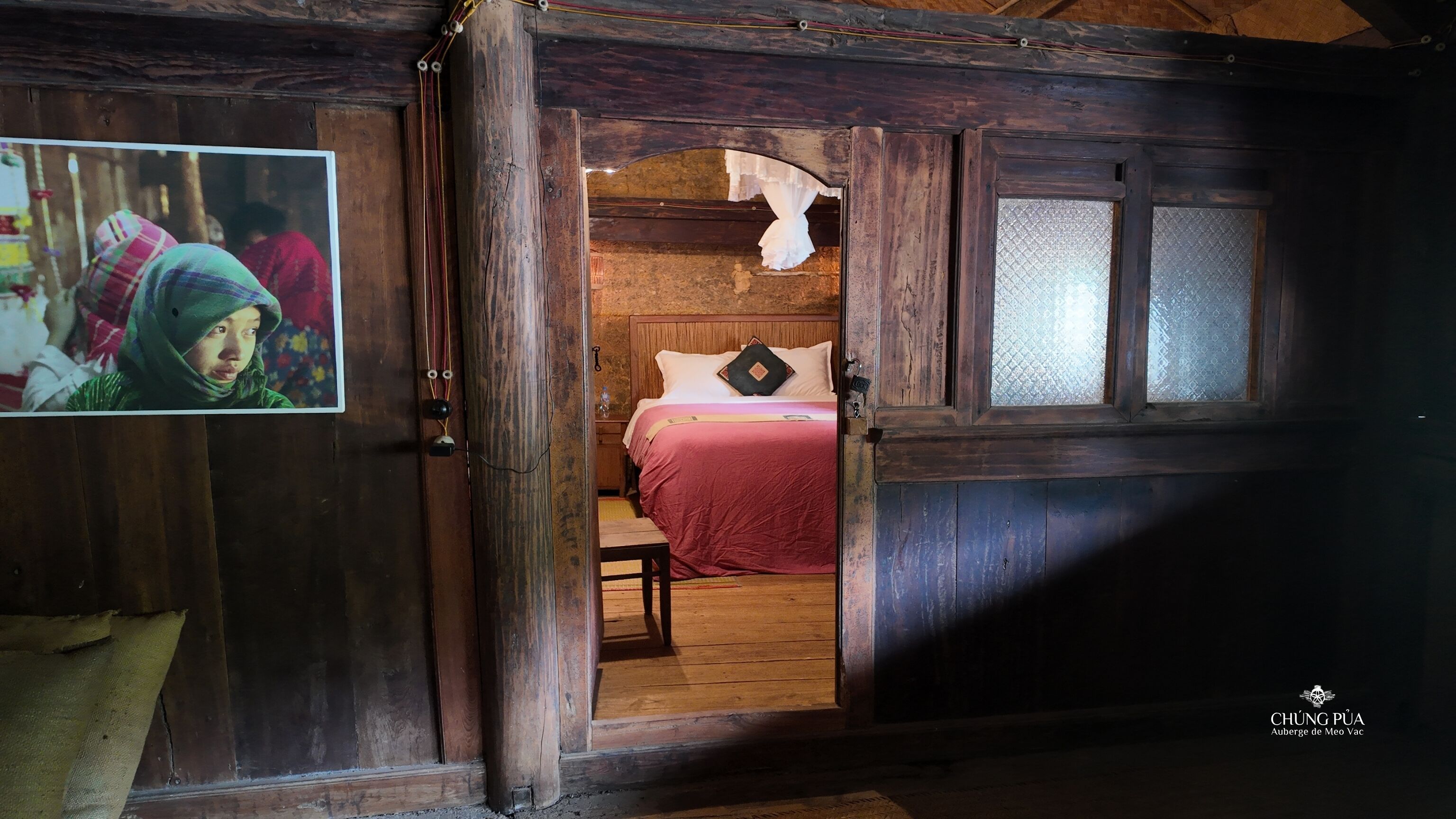 Um quarto rústico de madeira com uma cama, uma mesinha e um quadro pendurado na parede.
