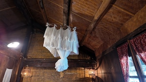 A rustic interior with a wooden ceiling, a hanging white garment, and a lantern. - Step Back in Time at L’Auberge de Meo Vac: A Century-Old H’mong Estate (Meo Vac)