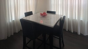 A dining area with a marble table, four chairs, a fruit bowl, and sheer curtains. - Modern Family Friendly Atlanta] Home - 4 miles to Mercedes-Benz Stadium (Atlanta)